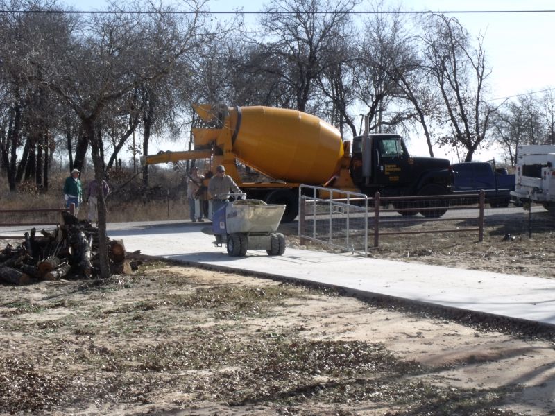 yellow cement truck with workers behind it near construction equipment
