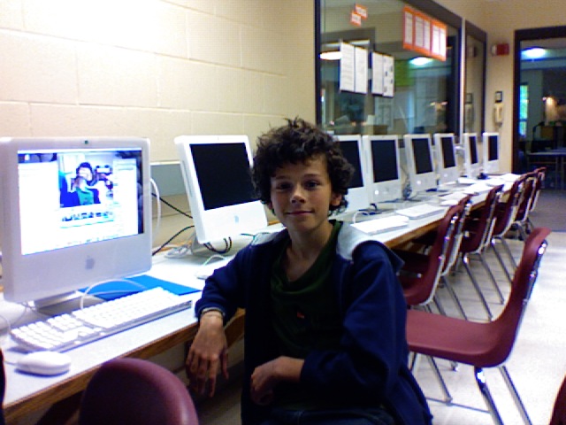 the child is sitting near a row of computers