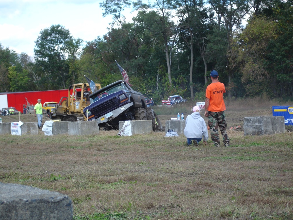 a man and a woman standing next to a truck on a grass field