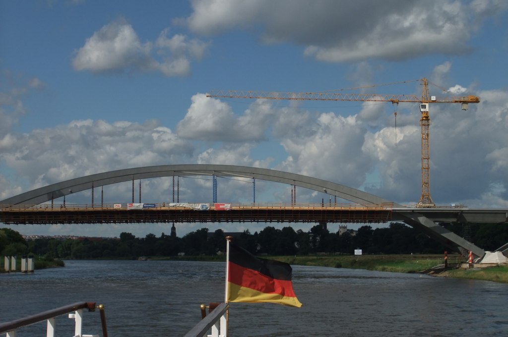a bridge with a tower crane near a river