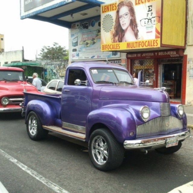 a purple old truck is parked near other old cars