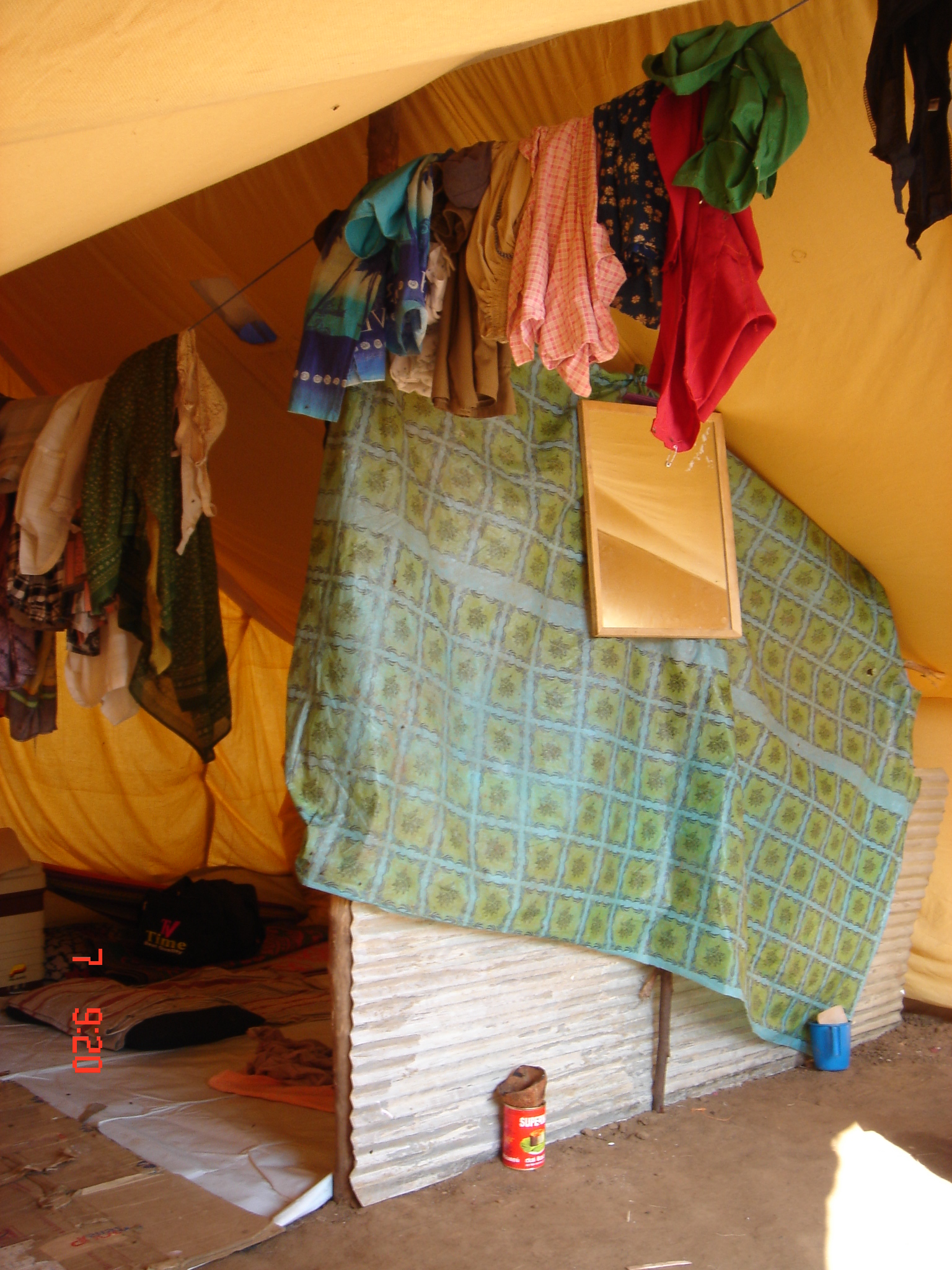 a bed covered in blankets next to a yellow tent