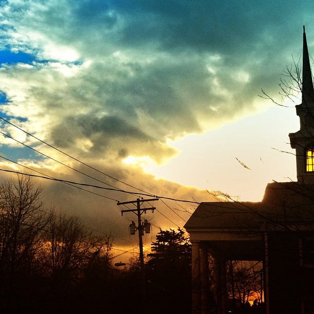 the silhouette of a church against an intense sunset