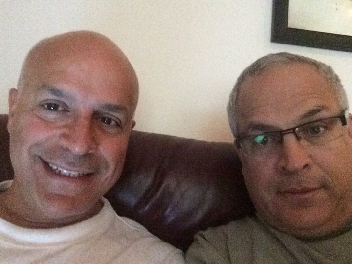 two men are sitting on a couch together
