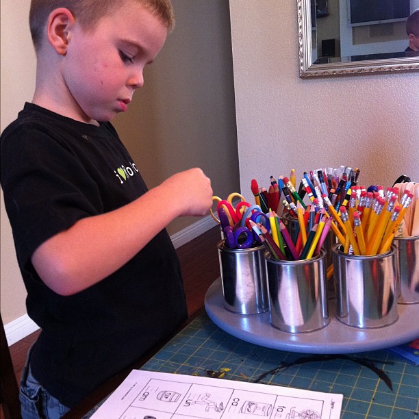 a boy is playing with colored pencils and paper