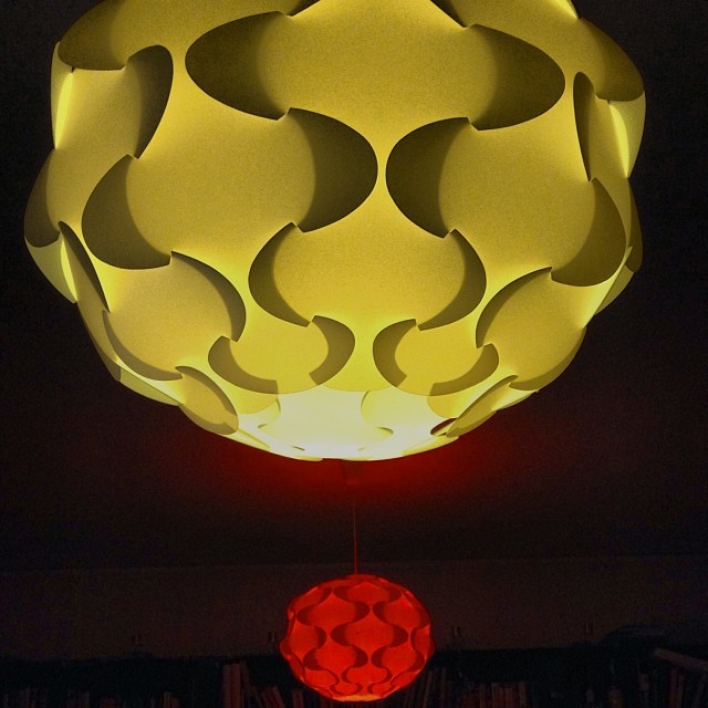 a light is hanging above a room with a bookcase in the background