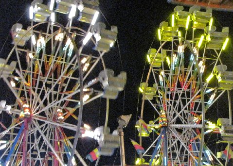 two ferriss on a carnival at night with lights on