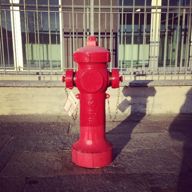 a red fire hydrant on a sidewalk in front of a building