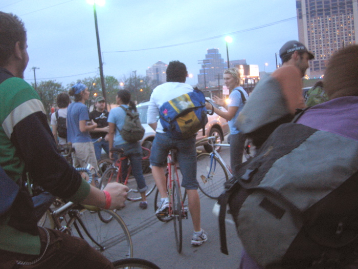 people and bicycles gathered on the streets outside at dusk