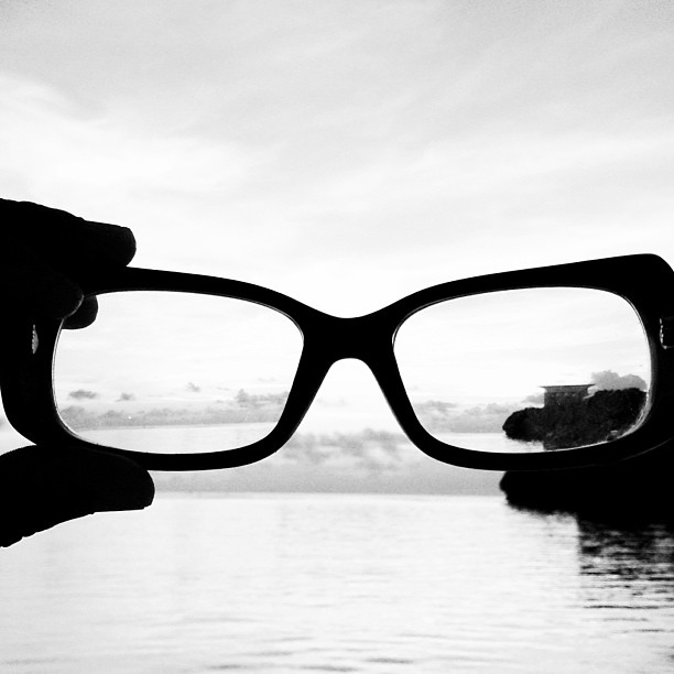 a pair of glasses sitting over water and a dock