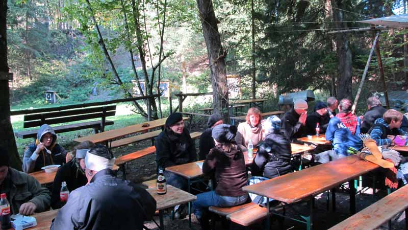 a group of people sitting at picnic tables in the forest