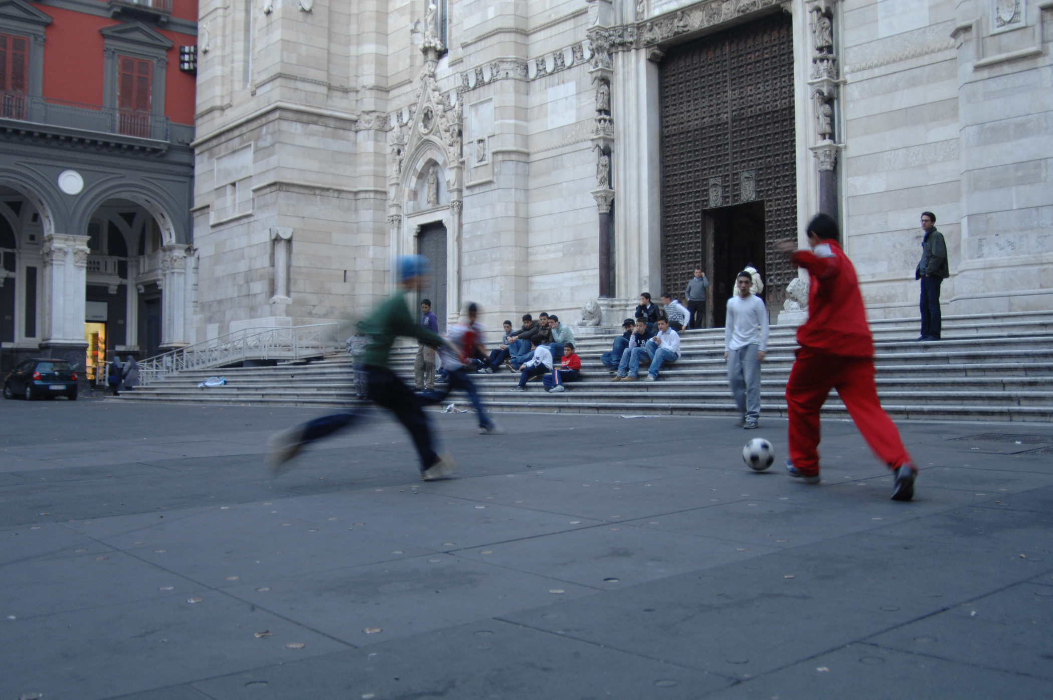 men kicking around in a plaza while people watch