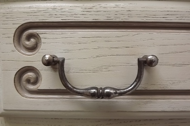 there is a white drawer with an aged handle