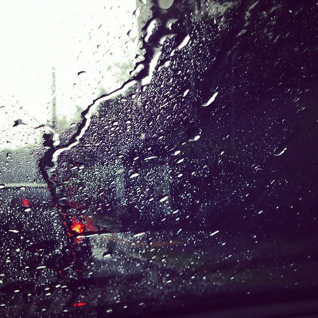 the view from inside of a car of streetlights, rain and traffic