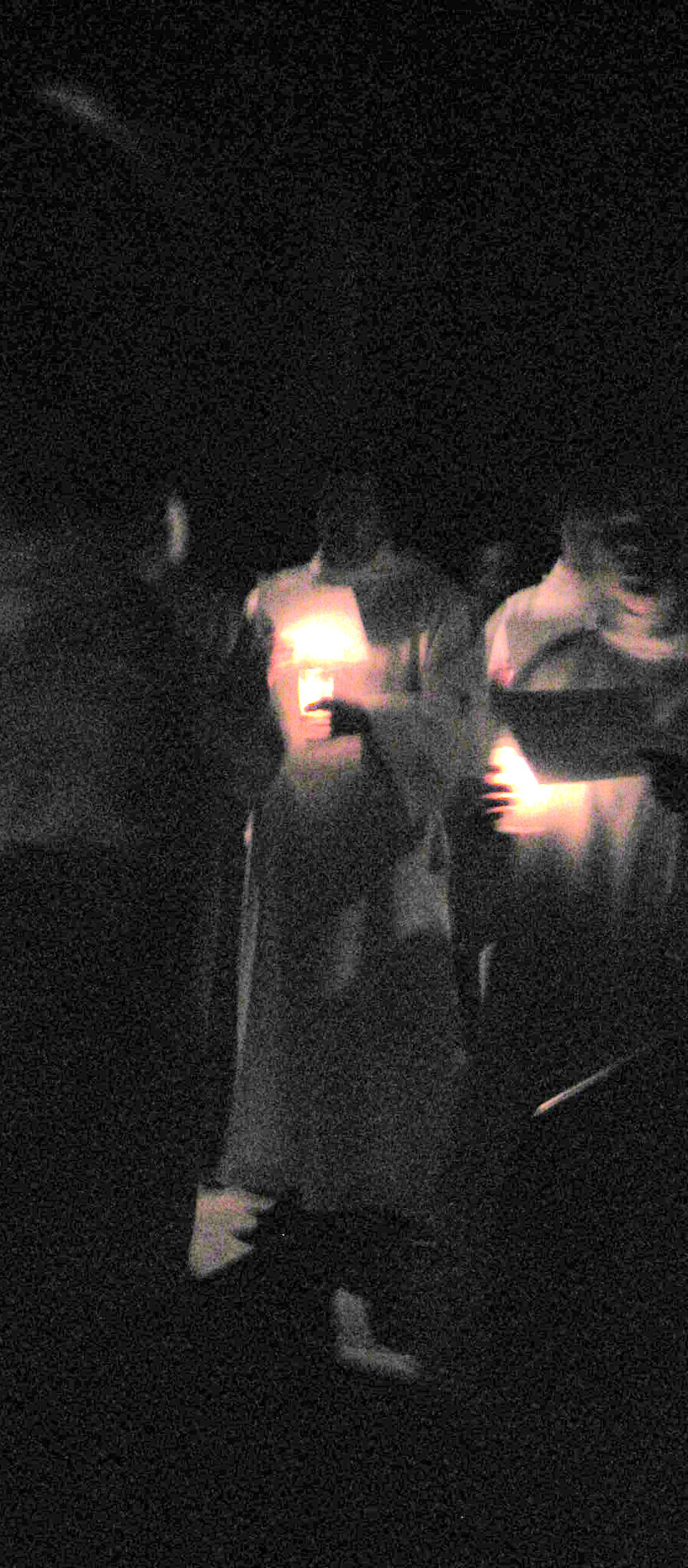 people in motion walking through an open dark space
