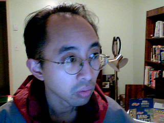 a man wearing glasses and a red jacket has a pair of scissors on his head