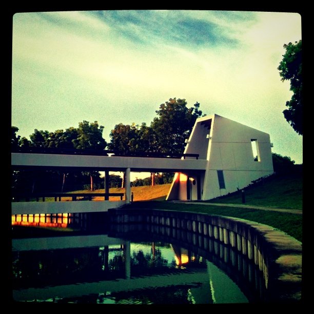 a large white building with a pond and trees in front