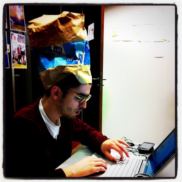 man with a brown bag on top of his head and a laptop