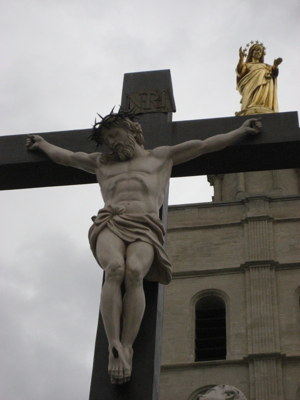 a cross is in front of a statue