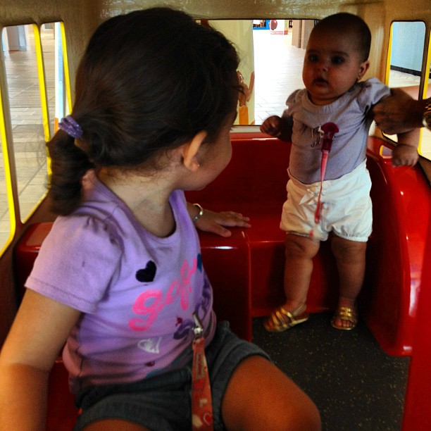 a little girl riding in a red train with another child