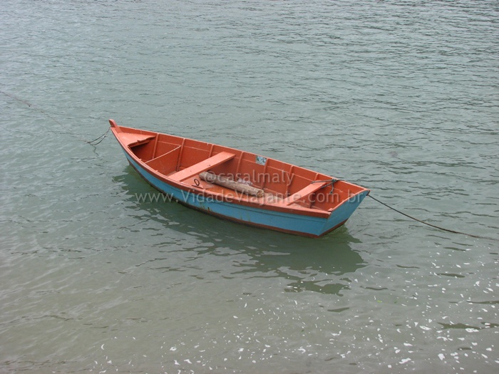the red and blue boat is sitting still in the water