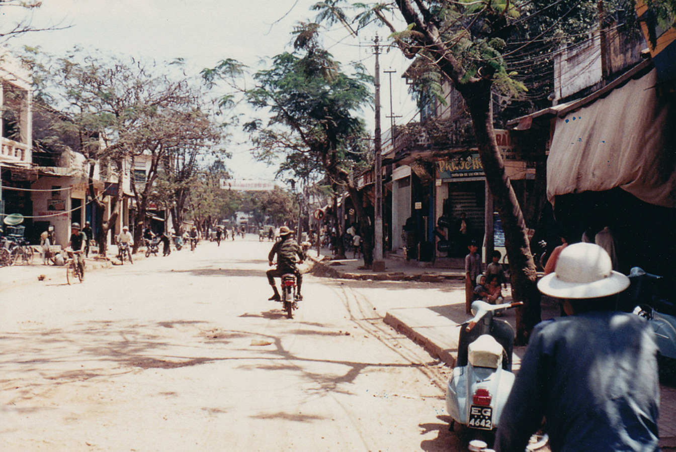 a dirt road with trees and people on it