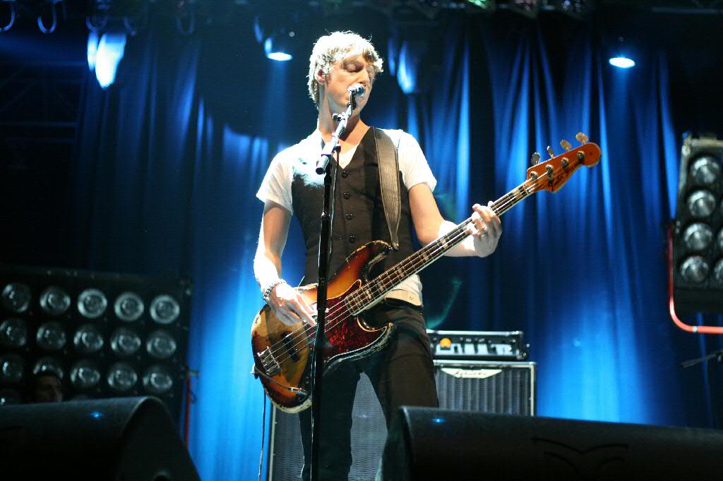 a man is standing in front of a microphone with an electric bass