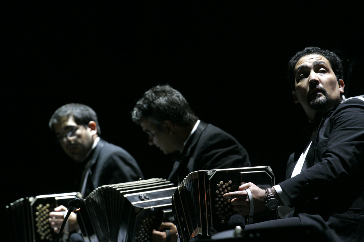 two guys holding up their accordions in dark lighting