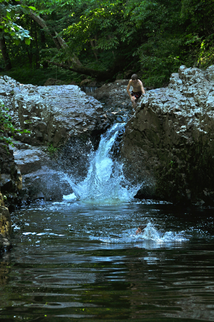two people playing in water near large rocks