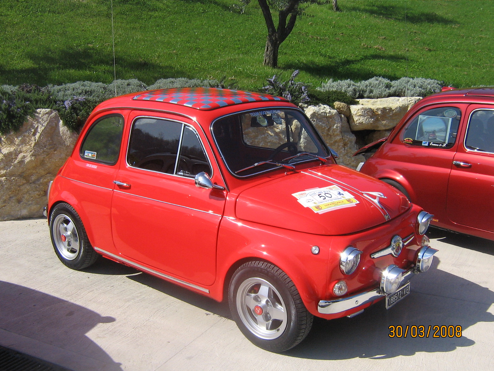 an old fashioned small red car in a parking lot