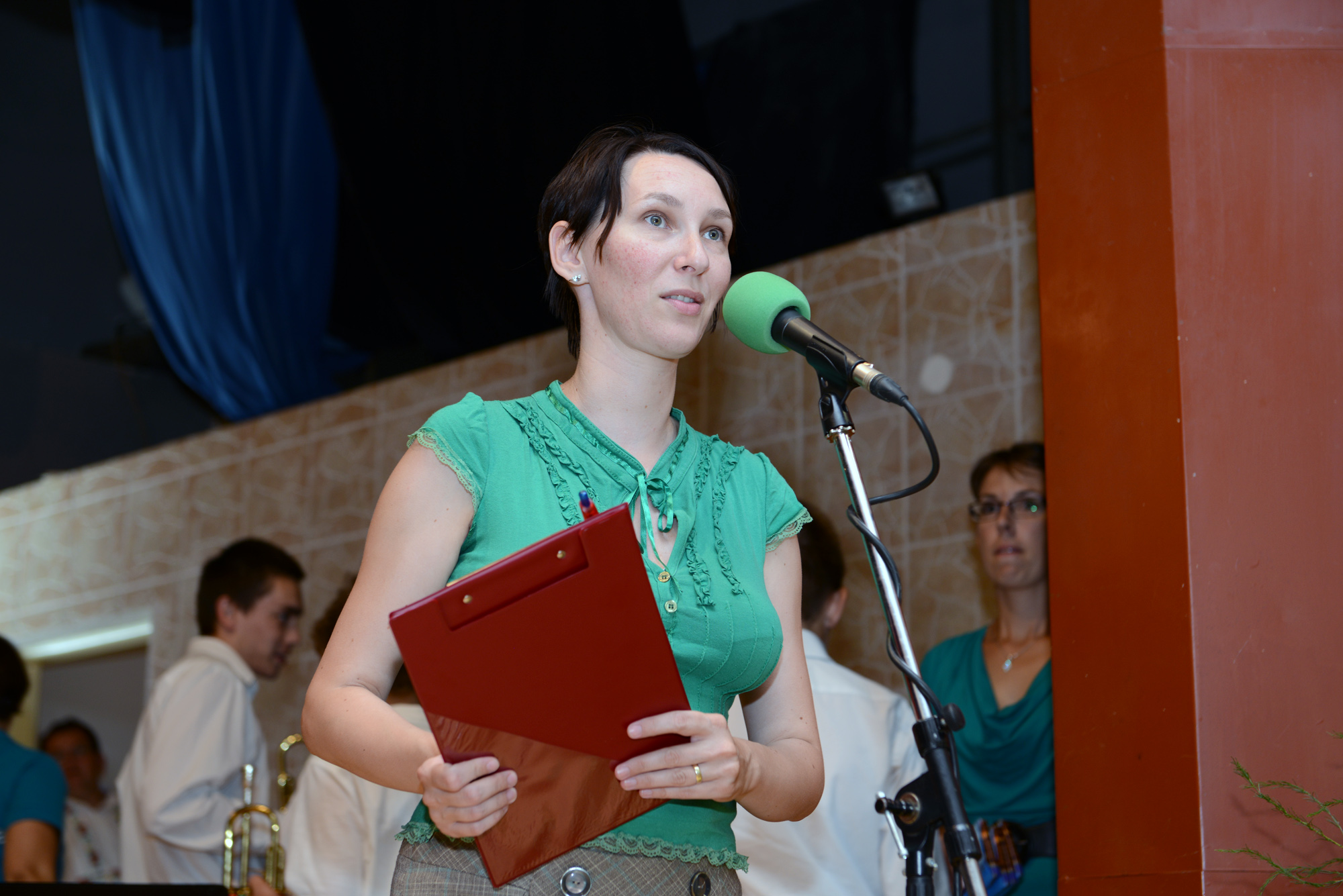 the young woman is speaking into a microphone while holding folders