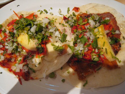 two tacos with different colored toppings on a white plate