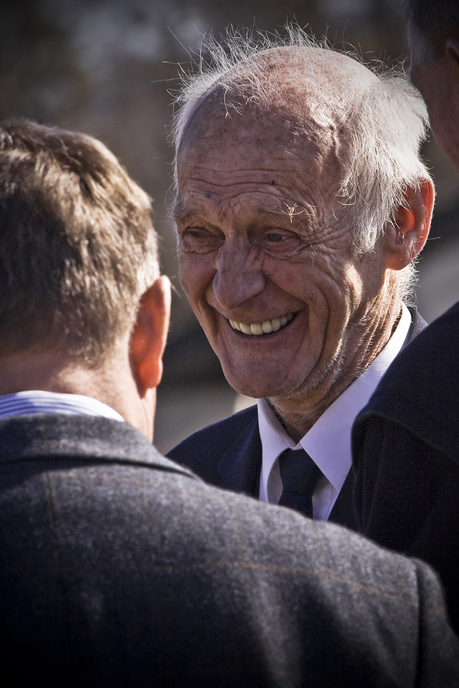 a man wearing a white hat smiling and talking to another man