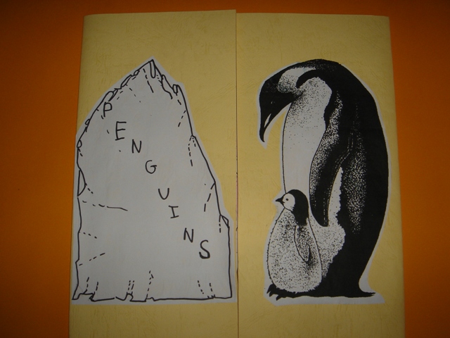 two papers with drawings of penguins next to a cliff