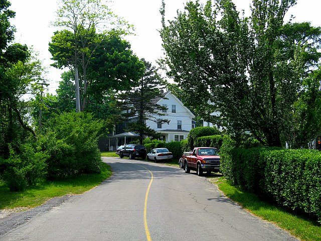 a narrow road that has some cars parked on the side