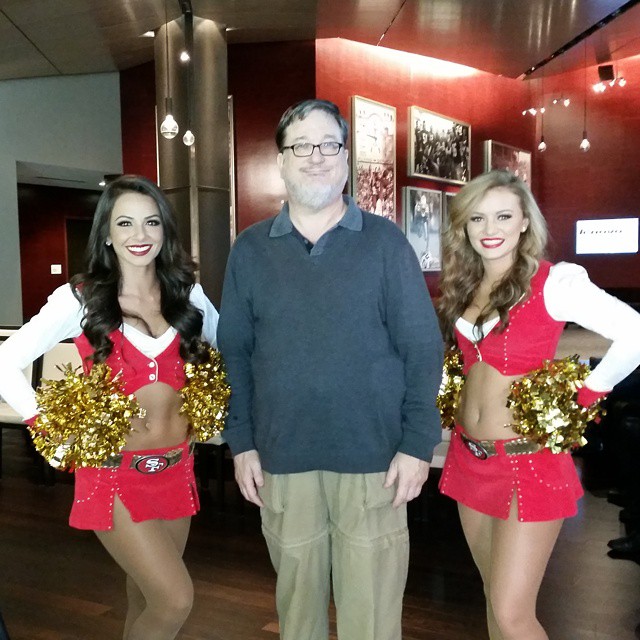 a man is standing with three women dressed in cheerleader outfits