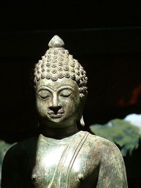 an old stone buddha statue is outside of a temple