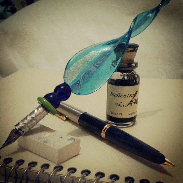 a fountain pen and pen with a bottle of ink next to it