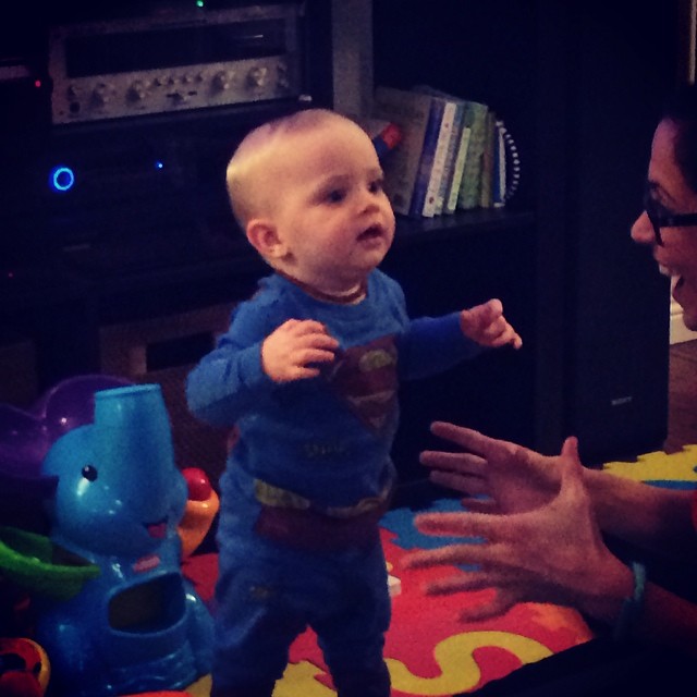 a baby in supermans costume standing next to a woman