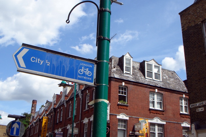 a street sign sitting next to a very tall red brick building