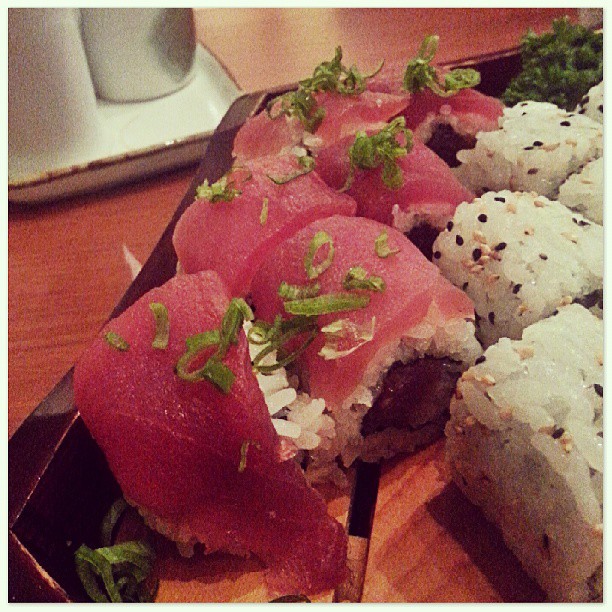 sushi platter sitting on a wooden table in front of a laptop