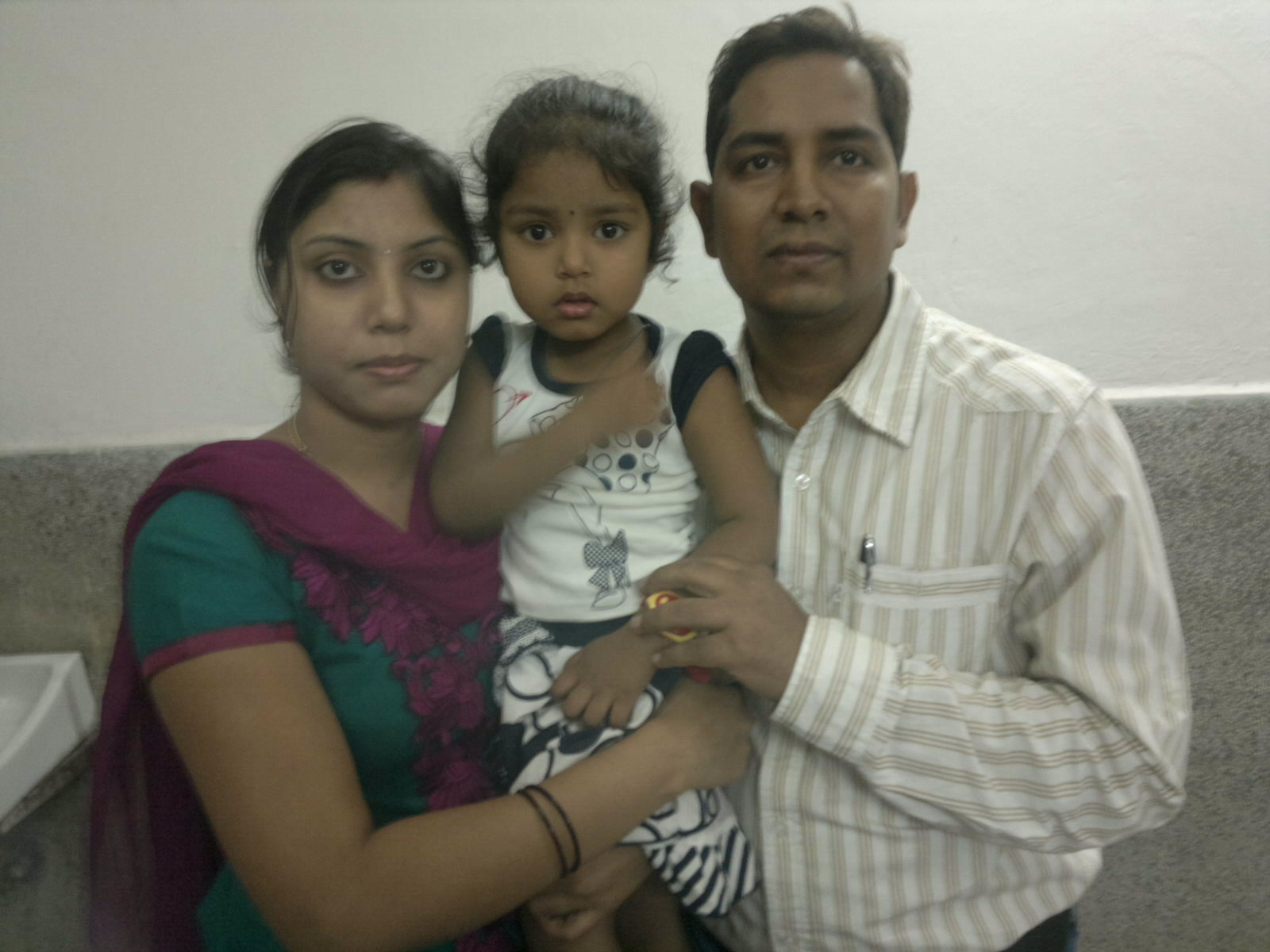 two young people posing for a picture with their hands on the shoulders of an adult who is holding a small child