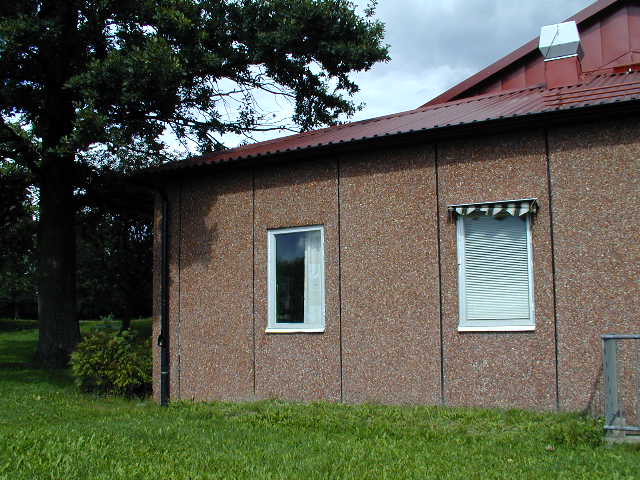 a brown brick house with two windows and red roof