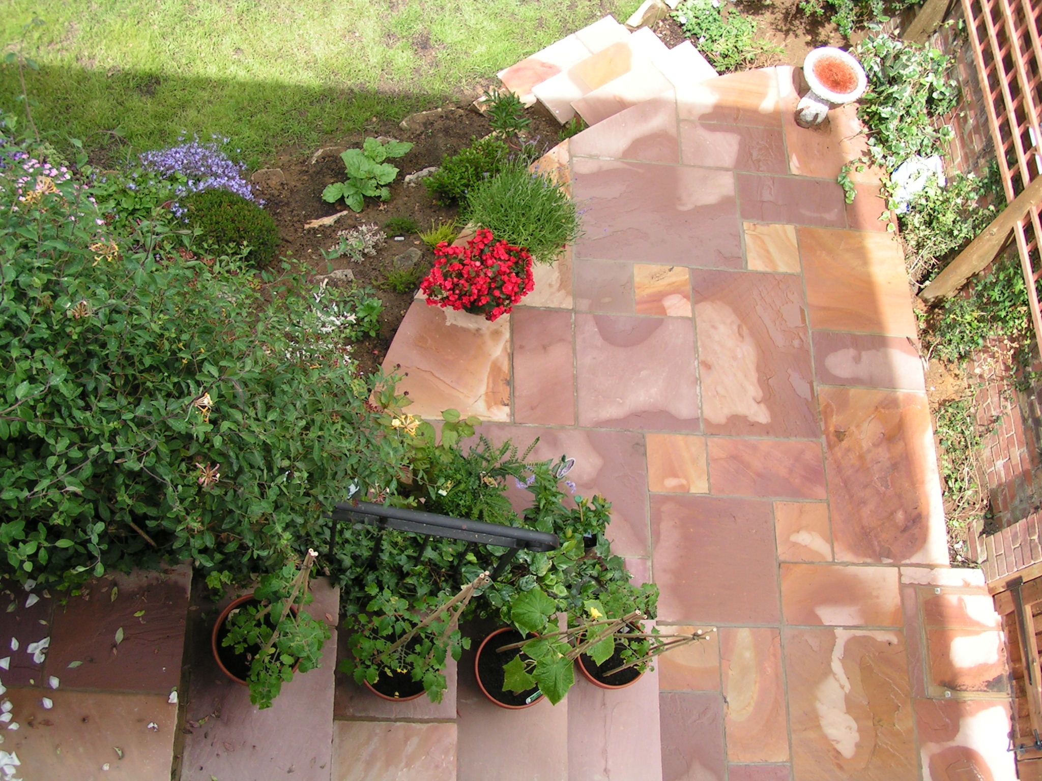 a stone patio that is covered with various types of plants