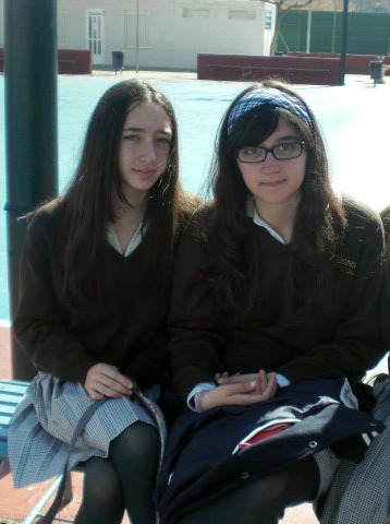 two women are sitting on a bench, one is wearing glasses