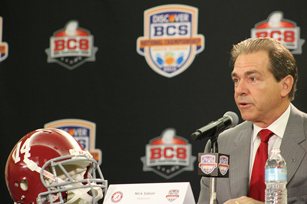 a football player in a suit and red tie sitting in front of a microphone