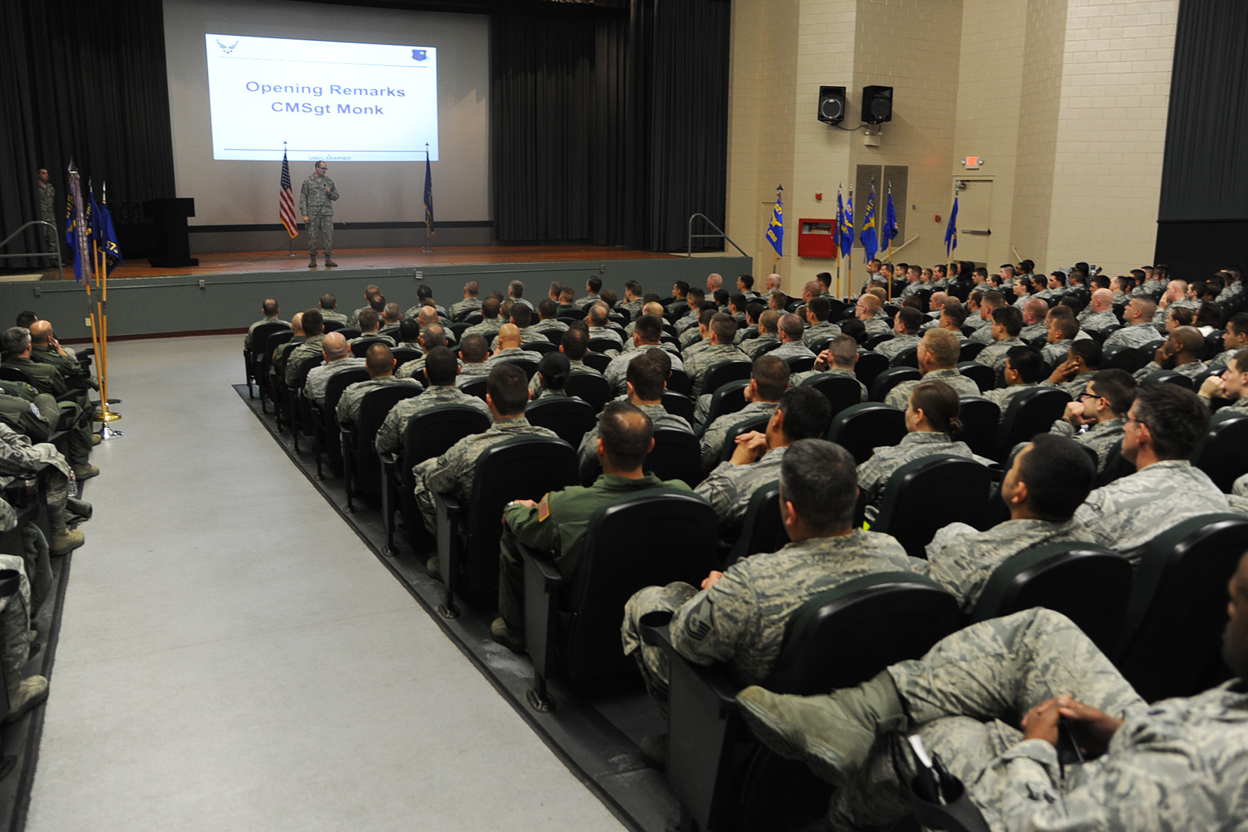 the military men are sitting in front of a large screen