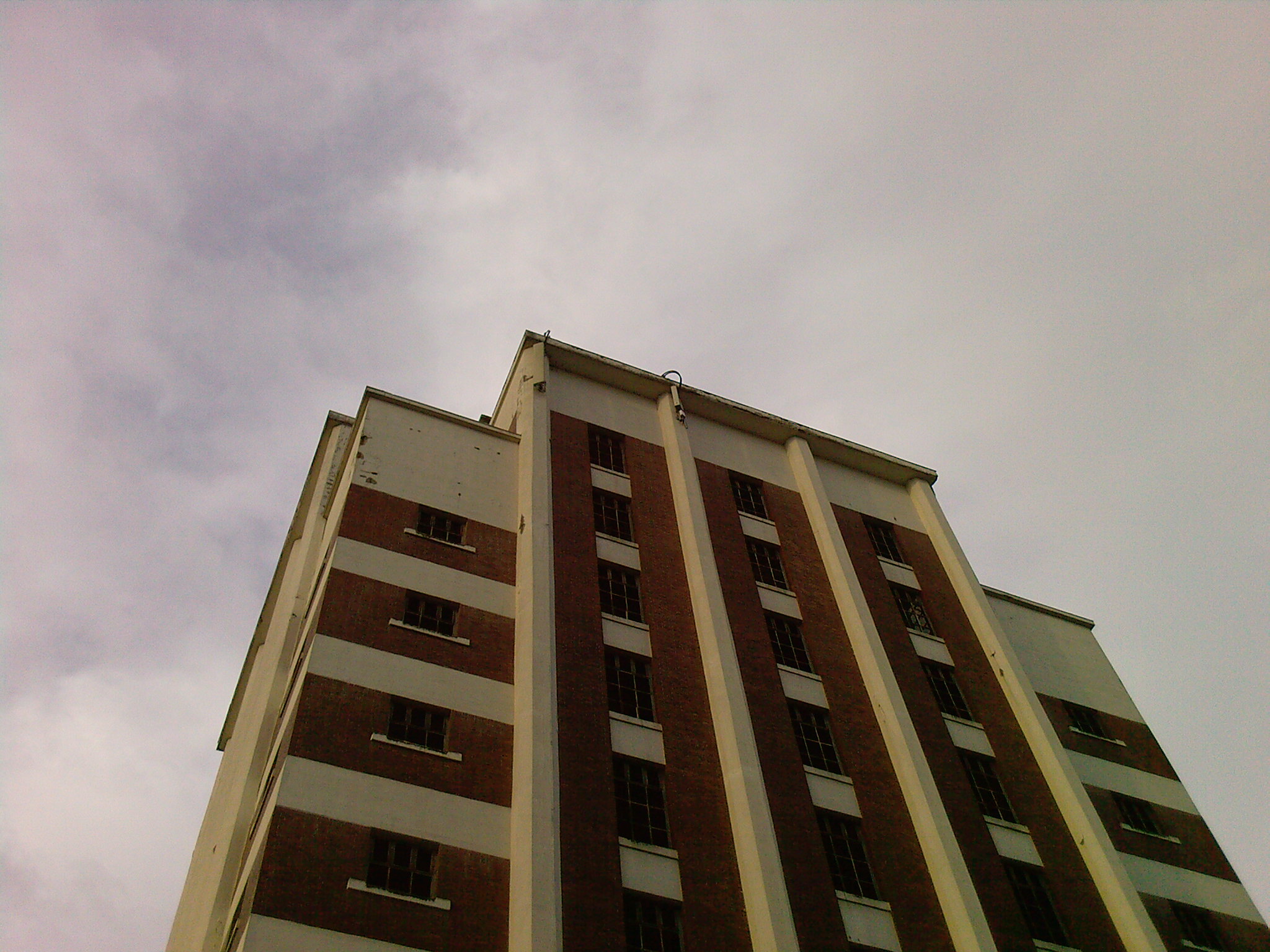 a tall building stands up against a cloudy sky