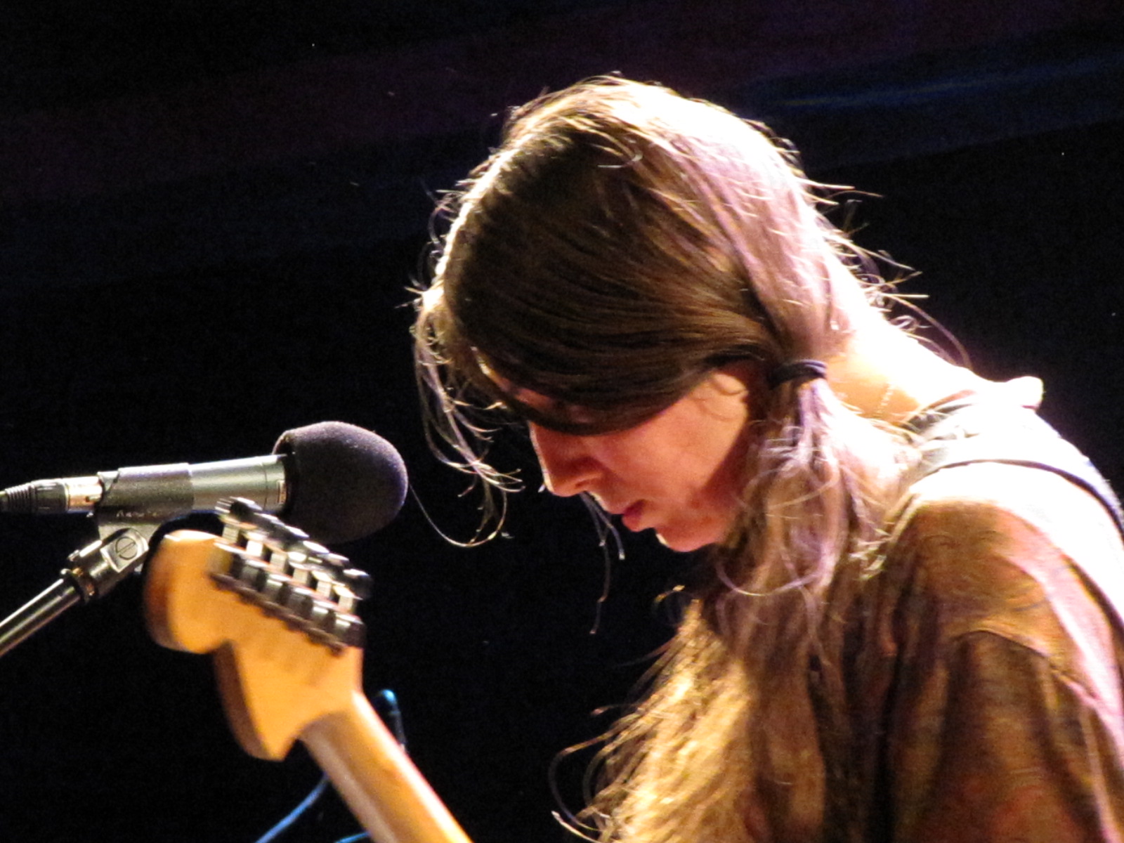 a young woman playing the guitar in front of microphone