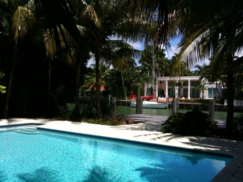 swimming pool and tropical setting in front of large house